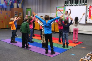 Students doing yogo with teacher on colorful mats Students doing yogo with teacher on colorful mats
